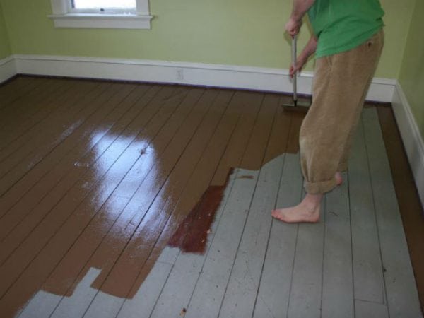 Mulher pinta um piso de madeira