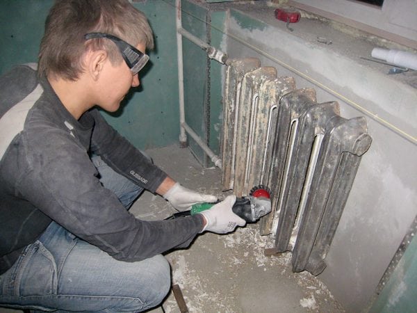 En mann fjerner gammel maling fra metall