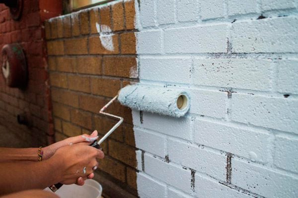 Aplicação de tinta em uma parede de tijolos