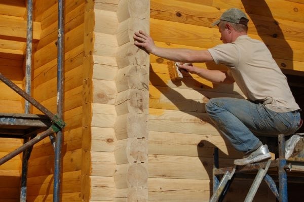 Proces malowania ścian drewnianego domu