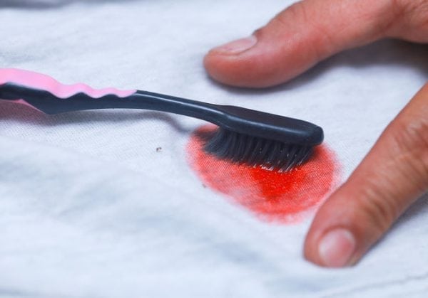 Enlever la peinture des vêtements avec une brosse à dents et un détachant