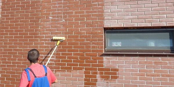 Nakładanie lakieru na ścianę z cegły za pomocą wałka