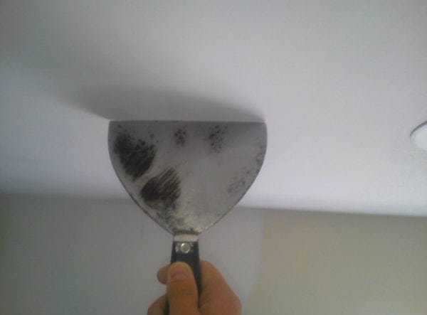 Usando uma espátula para limpar o teto