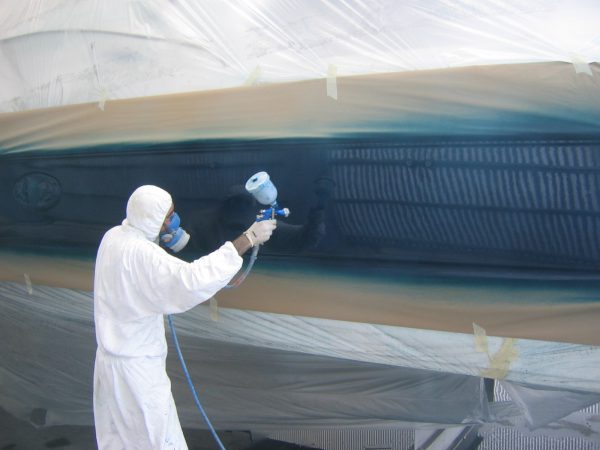 Pintando o casco do barco com uma pistola de pintura