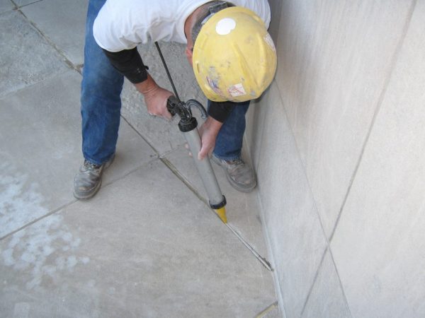 Vypĺňanie škár v betónovej podlahe zo stavebnej striekačky